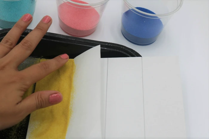 It's easy to create colored sand art with adhesive or sticky boards.